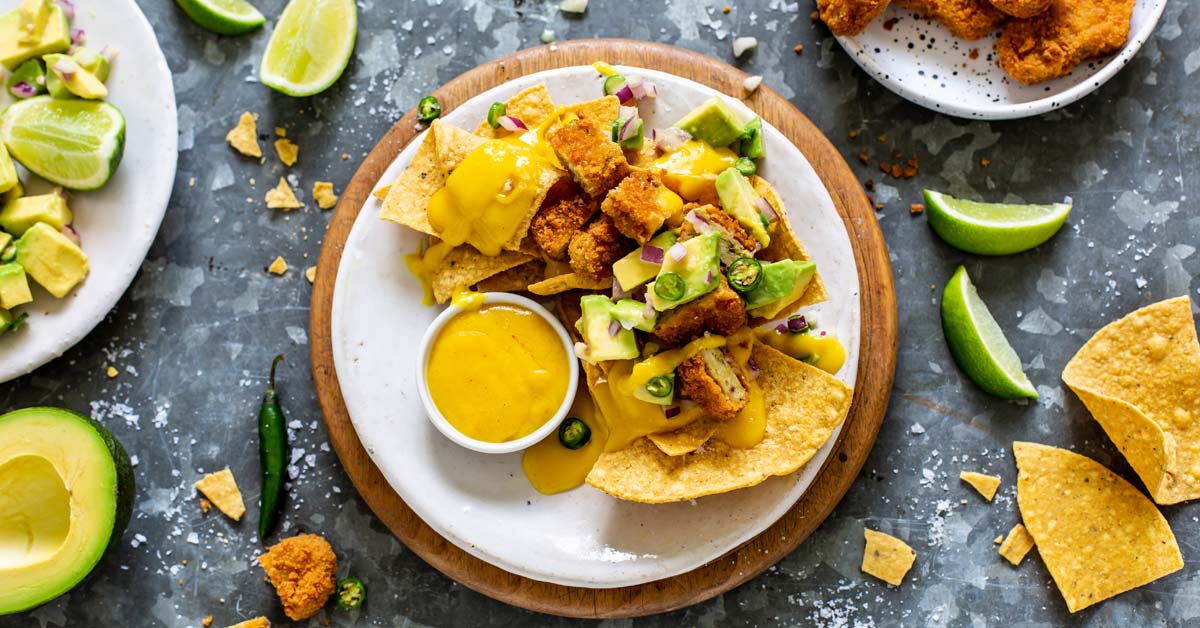 Cheesy Vegan Nachos topped with Nuggets and Salsa